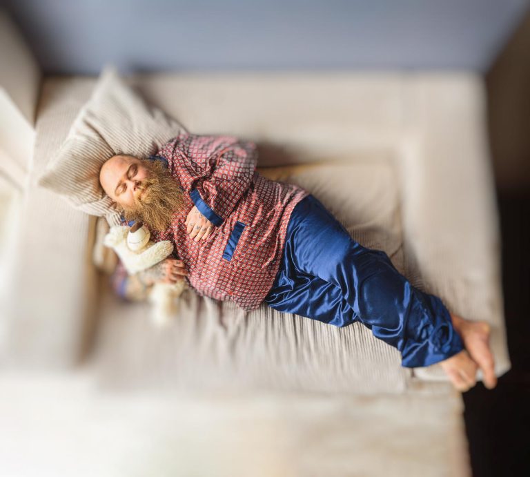 grande comfort uomo sovrappeso barba dorme sul divano orsacchiotto